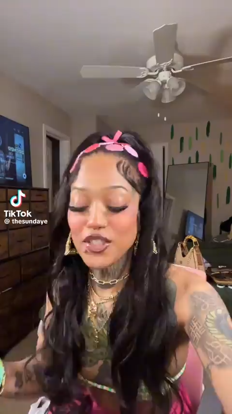 image of black woman sitting down facing camera and talking to camera while fixing outfit